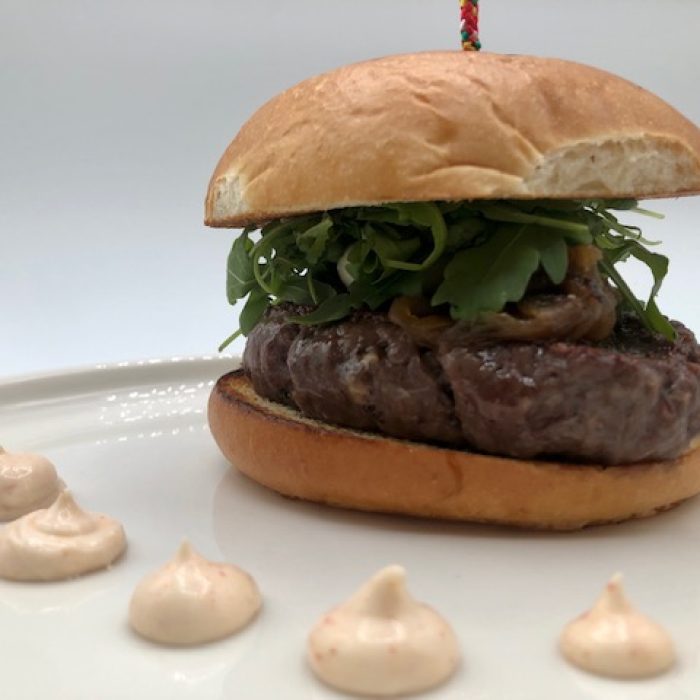 Hamburguesa de vaca, crema de queso de cabra y cebolla caramelizada en pan brioche (200g)
