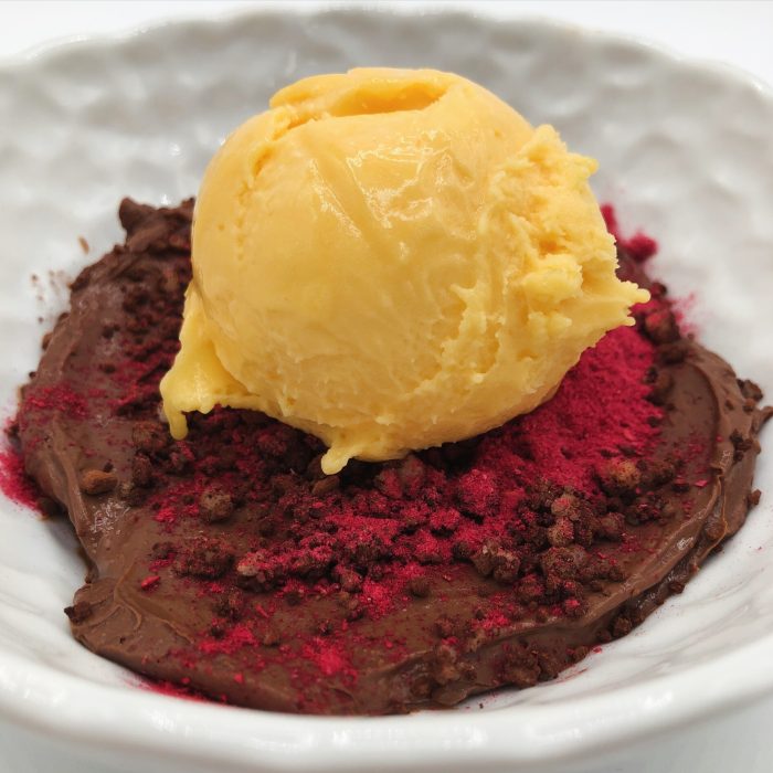 Cremoso de chocolate negro, arena de cacao, helado de mango y frambuesa liofilizada
